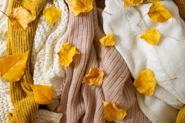 Pile de vêtements tricotés avec des feuilles d'automne, fond chaud, tricot, espace pour le texte — Photo