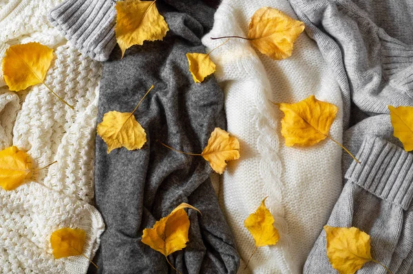 Pile de vêtements tricotés avec des feuilles d'automne, fond chaud, tricot, espace pour le texte — Photo