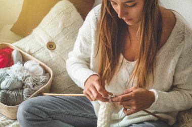 Güzel kız yatakta sıcak bir kazak örer. Örgü için aksesuarlar.