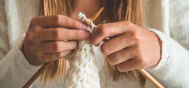 Güzel kız yatakta sıcak bir kazak örer. Örgü için aksesuarlar.