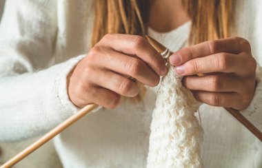 Güzel kız yatakta sıcak bir kazak örer. Örgü için aksesuarlar.