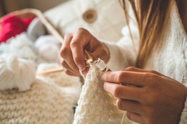 Güzel kız yatakta sıcak bir kazak örer. Örgü için aksesuarlar.