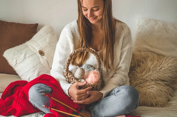 Mooi meisje knits een warme trui op het bed. Accessoires voor breien. — Stockfoto