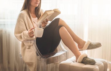 Güzel kız sıcak çay bir fincan ile bir kitap okuyor. Sonbahar Kış Saati.