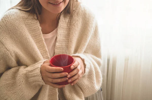 Mujer con una taza de bebida caliente junto a la ventana. Mirando la ventana y bebiendo té. Buenos días con el té. — Foto de Stock