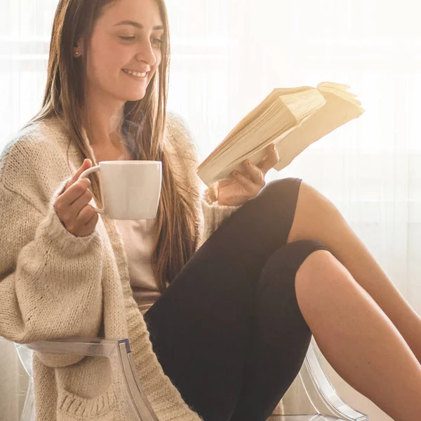 Krásná dívka si čte knihu s šálkem horkého čaje. Podzim zimní čas. — Stock fotografie