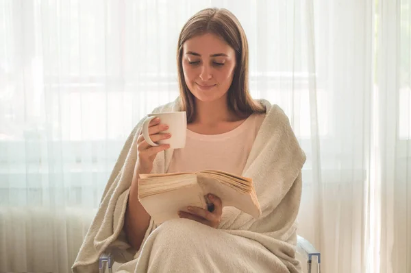 Hermosa chica está leyendo un libro con una taza de té caliente. Otoño Invierno . — Foto de Stock