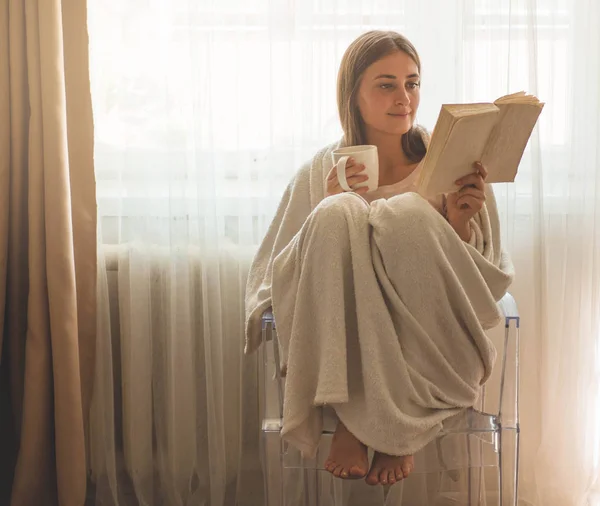Güzel kız sıcak çay bir fincan ile bir kitap okuyor. Sonbahar Kış Saati. — Stok fotoğraf
