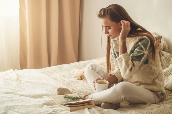 Krásná dívka si čte knihu s šálkem horkého čaje. Podzim zimní čas. — Stock fotografie