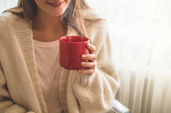 Vrouw met kopje warme drank bij het raam. Kijkend naar het raam en Drink thee. Goedemorgen met thee. — Stockfoto