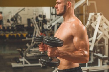 Spor salonunda beden eğitimi hocası. Kas formundaki ve ince vücutlu erkek model.