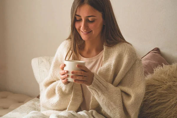 Cozy Autumn winter evening. Woman drinking hot tea and relaxing at home.