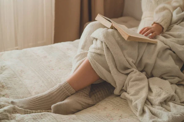 Przytulny jesienny zimowy wieczór. Kobieta pije gorącą herbatę i czyta książkę. — Zdjęcie stockowe