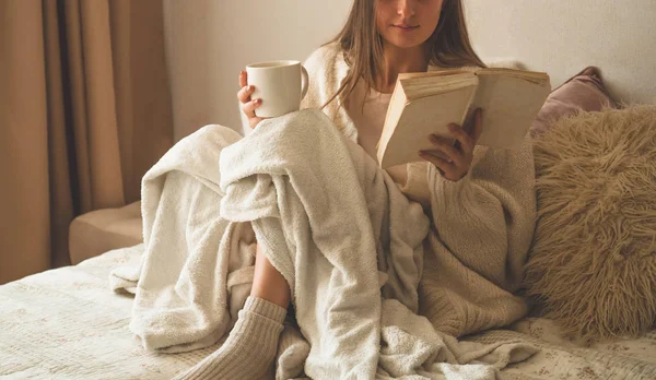 Acogedora noche de invierno de otoño. Mujer bebiendo té caliente y leyendo libro . — Foto de Stock