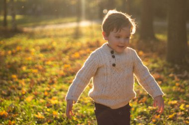 Küçük mutlu çocuk sonbaharda gülüyor ve oynuyor.