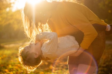 Anne ve oğlu parkta yürüyor ve güzel sonbahar doğasının tadını çıkarıyorlar.