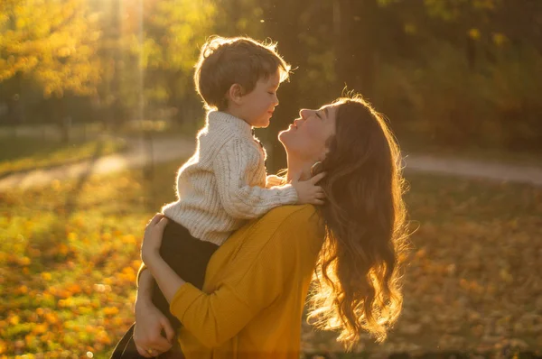 Moeder en zoon wandelen in het park en genieten van de prachtige herfstnatuur — Stockfoto