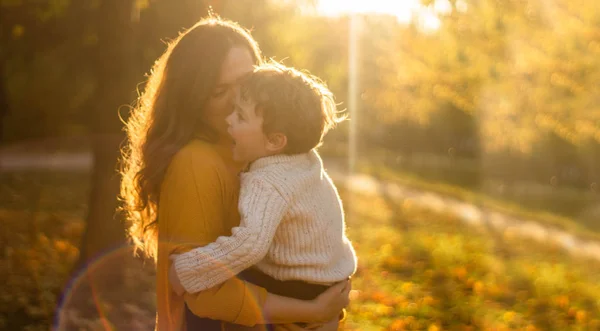 Moeder en zoon wandelen in het park en genieten van de prachtige herfstnatuur — Stockfoto