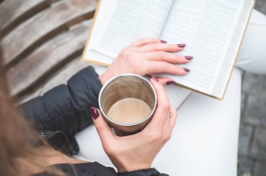 Kızın elinde kitap var. Bankta oturan, kitap okuyan kız.. 