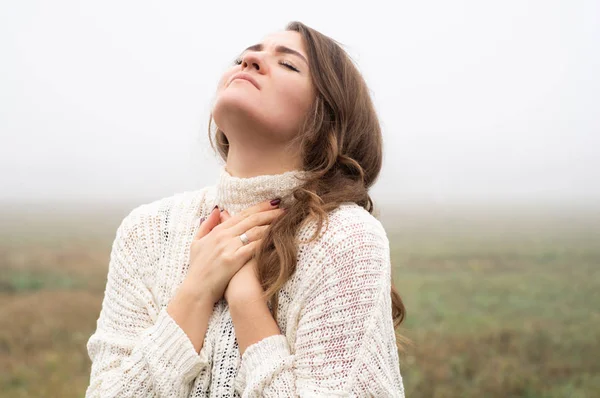 Chica cerró los ojos, rezando en un campo durante la hermosa niebla. Manos dobladas en concepto de oración por la fe — Foto de Stock
