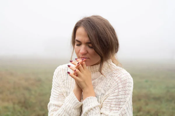 Chica cerró los ojos, rezando en un campo durante la hermosa niebla. Manos dobladas en concepto de oración por la fe — Foto de Stock