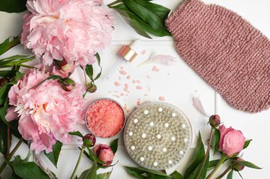 Beyaz arka planda pembe şakayık çiçekleri olan doğal organik kozmetik ürünler. Spa rahatlama tedavileri ve anti-selülit masajı