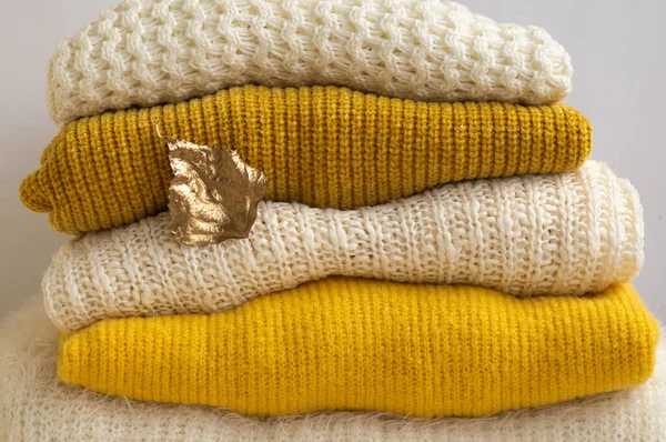 Autumn winter concept. Pile of knitted clothes with autumn gold leaves, warm background, knitwear — Stock Photo, Image