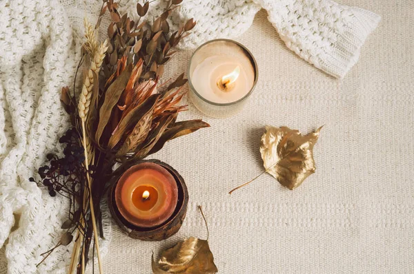 Fondo con suéteres cálidos, velas y ramo de flores secas. Bodegón acogedor en tonos cálidos —  Fotos de Stock