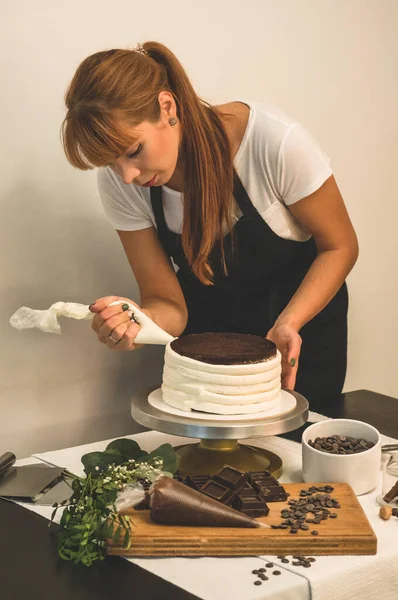 Confectioner girl is preparing a cake. The concept of pastry, cooking cakes