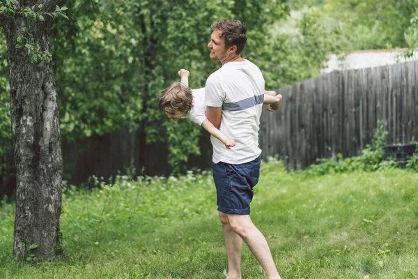 Vater und Sohn spielen und umarmen sich im Freien. Vatertagskonzept. — Stockfoto