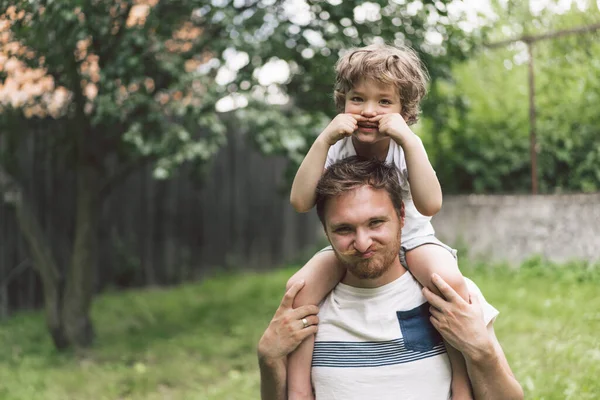 Vater und Sohn spielen und umarmen sich im Freien. Vatertagskonzept. — Stockfoto