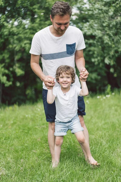 Vater und Sohn spielen und umarmen sich im Freien. Vatertagskonzept. — Stockfoto