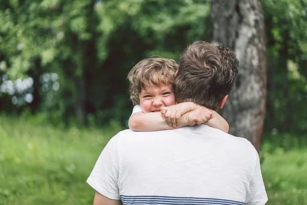 Vater und Sohn spielen und umarmen sich im Freien. Vatertagskonzept. — Stockfoto