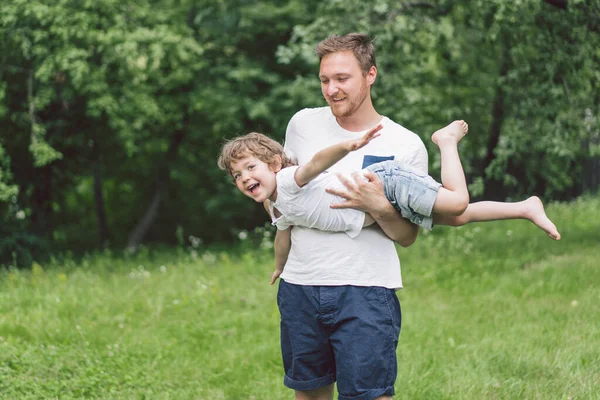 Vater und Sohn spielen und umarmen sich im Freien. Vatertagskonzept. — Stockfoto