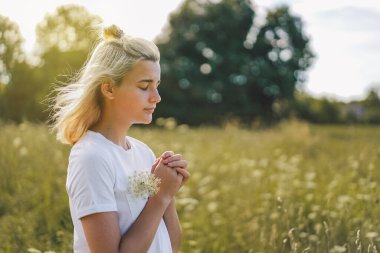 Kız gözlerini kapattı, tarlada dua ediyordu. İnanç için dua kavramına sarılmış eller.