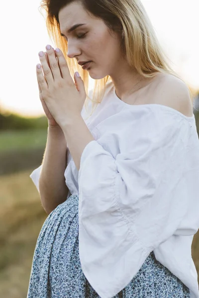 Pregnant woman praying outdoors on at sunset. Concept for faith, spirituality and religion. — Stock Photo, Image