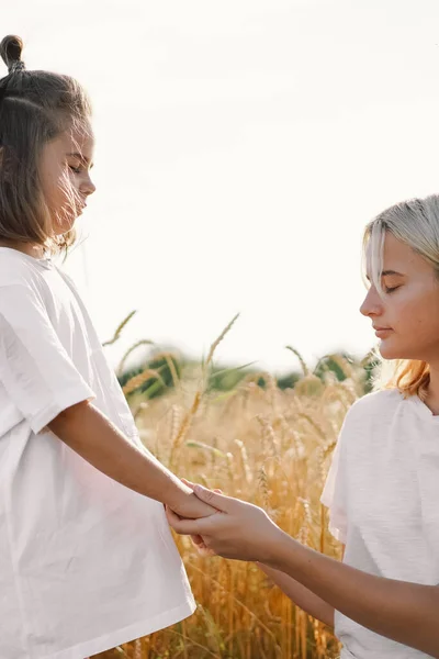 Meisjes bidden en hand in hand in een tarweveld. Bid voor God dat elkaar steunen. — Stockfoto