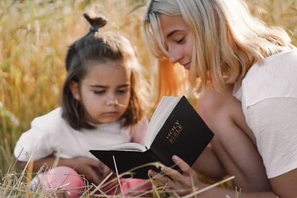 Girls reading holy bible in a wheat field. Study the holy bible together