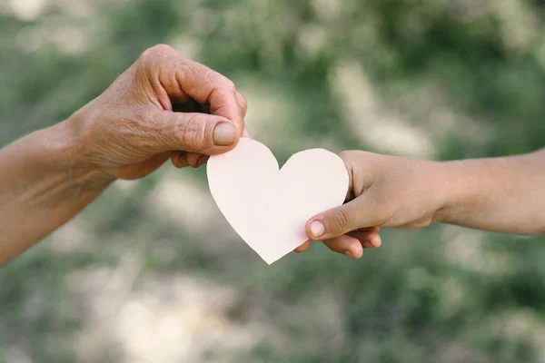 Childs mano y vieja mano abuela celebrar el corazón. — Foto de Stock