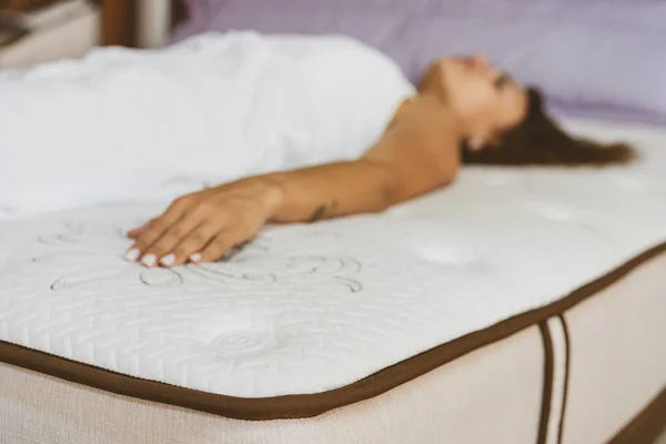 Mujer probando colchón en tienda de muebles. El concepto de llenar un colchón. — Foto de Stock