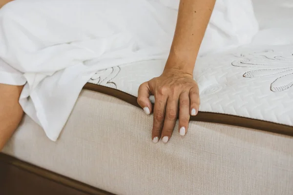 ผู้หญิงทดสอบที่นอนในร้านเฟอร์นิเจอร์ แนวคิดของการเติมที่นอน . — ภาพถ่ายสต็อก