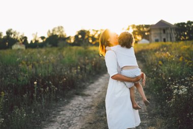 Gün batımında sahada çocuğuyla oynayan bir kadın.