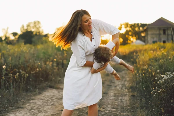 Donna che gioca con il suo bambino sul campo durante il tramonto — Foto Stock