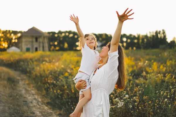 Donna che gioca con il suo bambino sul campo durante il tramonto — Foto Stock