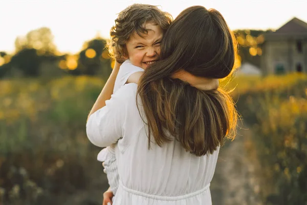 Woman playing with her child on the field during sunset — Stock Photo, Image