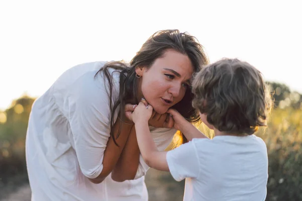 Frau spielt bei Sonnenuntergang mit ihrem Kind auf dem Feld — Stockfoto