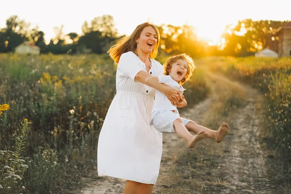 Donna che gioca con il suo bambino sul campo durante il tramonto — Foto Stock