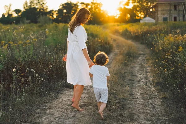 Donna che gioca con il suo bambino sul campo durante il tramonto — Foto Stock