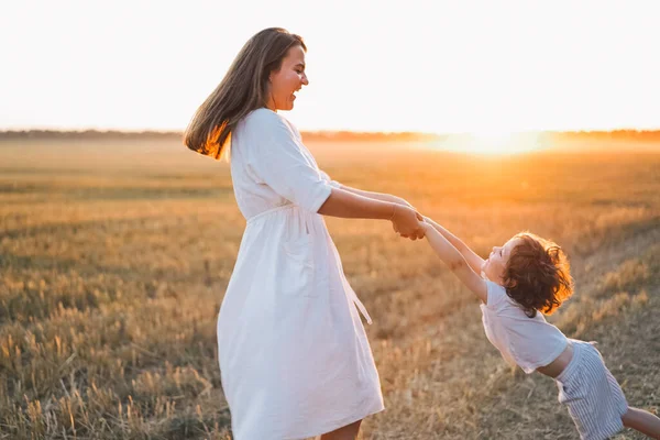 Donna che gioca con il suo bambino sul campo durante il tramonto — Foto Stock