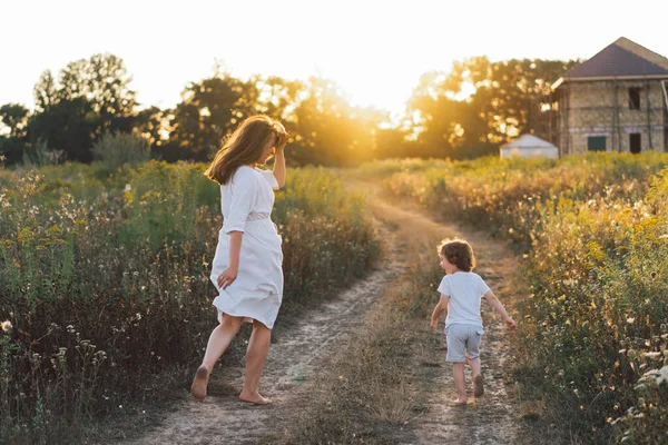 Donna che gioca con il suo bambino sul campo durante il tramonto — Foto Stock